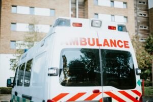White ambulance parked outside a brick apartment building, viewed from the rear.