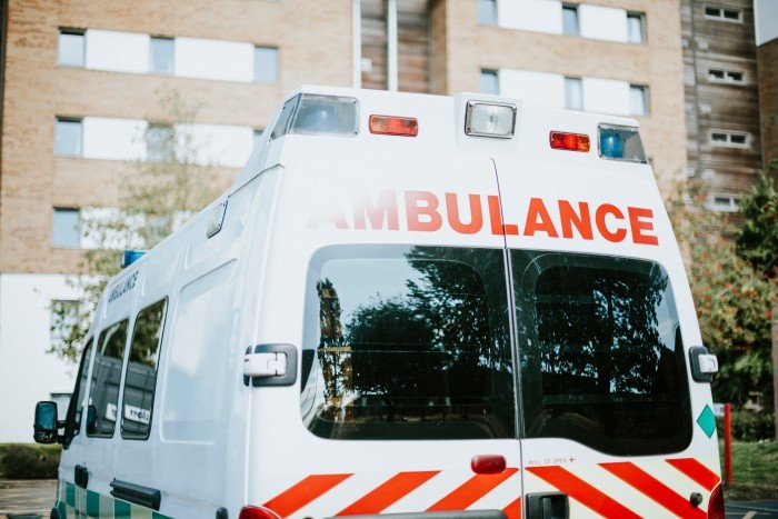 White ambulance parked outside a brick apartment building, viewed from the rear.