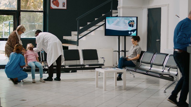 Doctor examining a young child with family members in a hospital waiting area