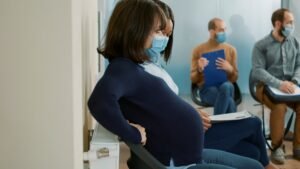 Pregnant woman wearing a face mask sits in a waiting room