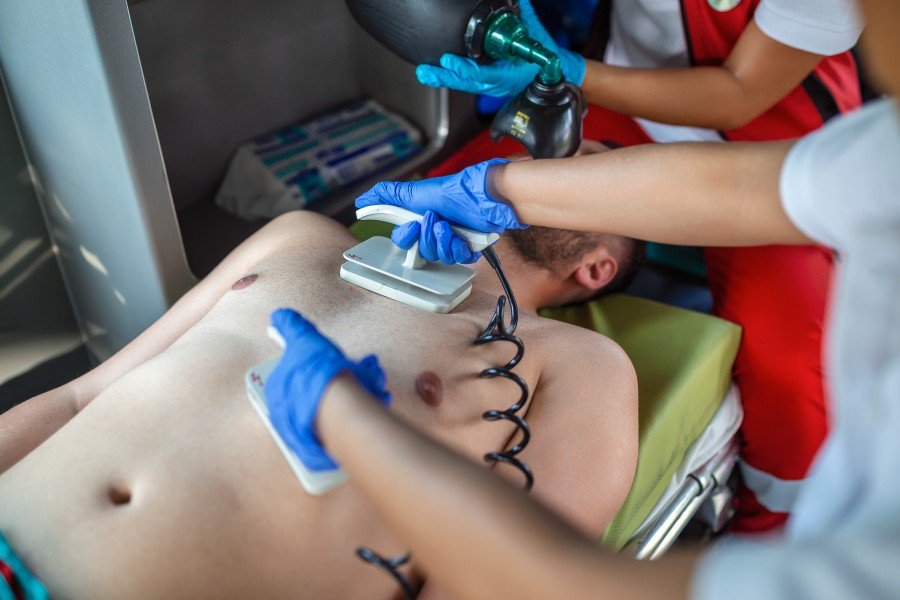 Emergency Medical Care providers perform chest resuscitation on an injured patient inside an ambulance.